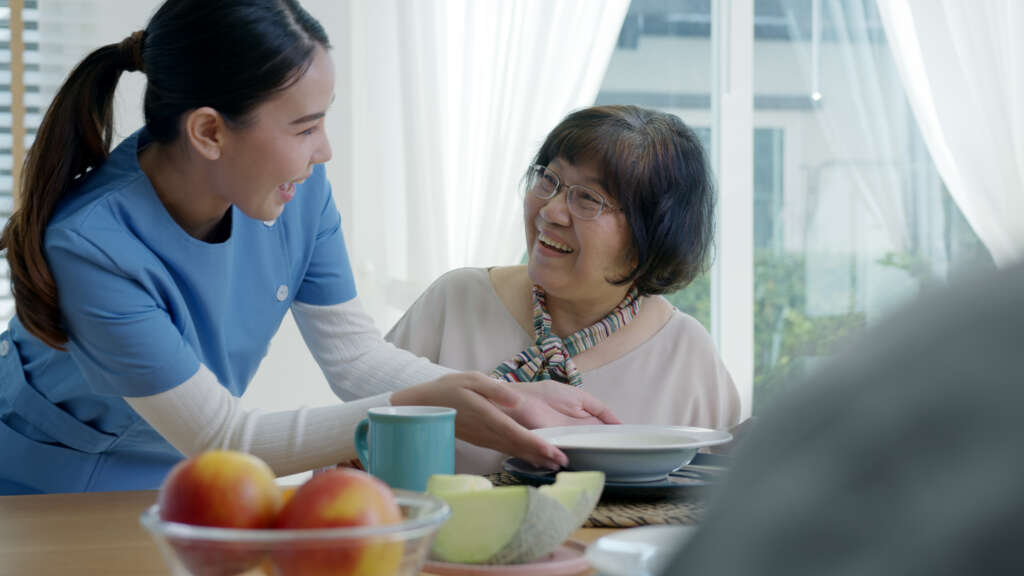 a domestic helper in Singapore assisting an elderly woman in her meal