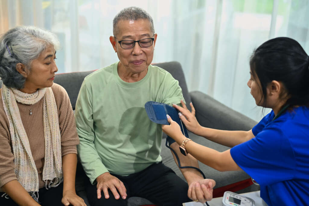 Elderly man having blood pressure checked at home as part of elderly care support arranged by the best maid agency in Singapore