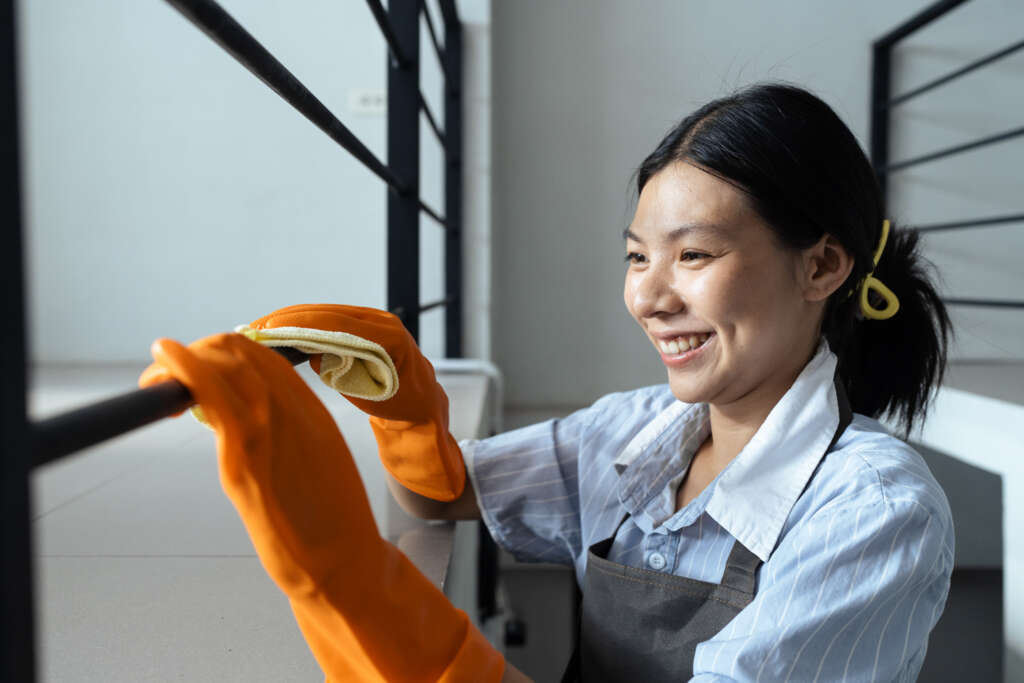 Filipino domestic helper cleaning stair railing, placed through a filipino maid agency in Singapore